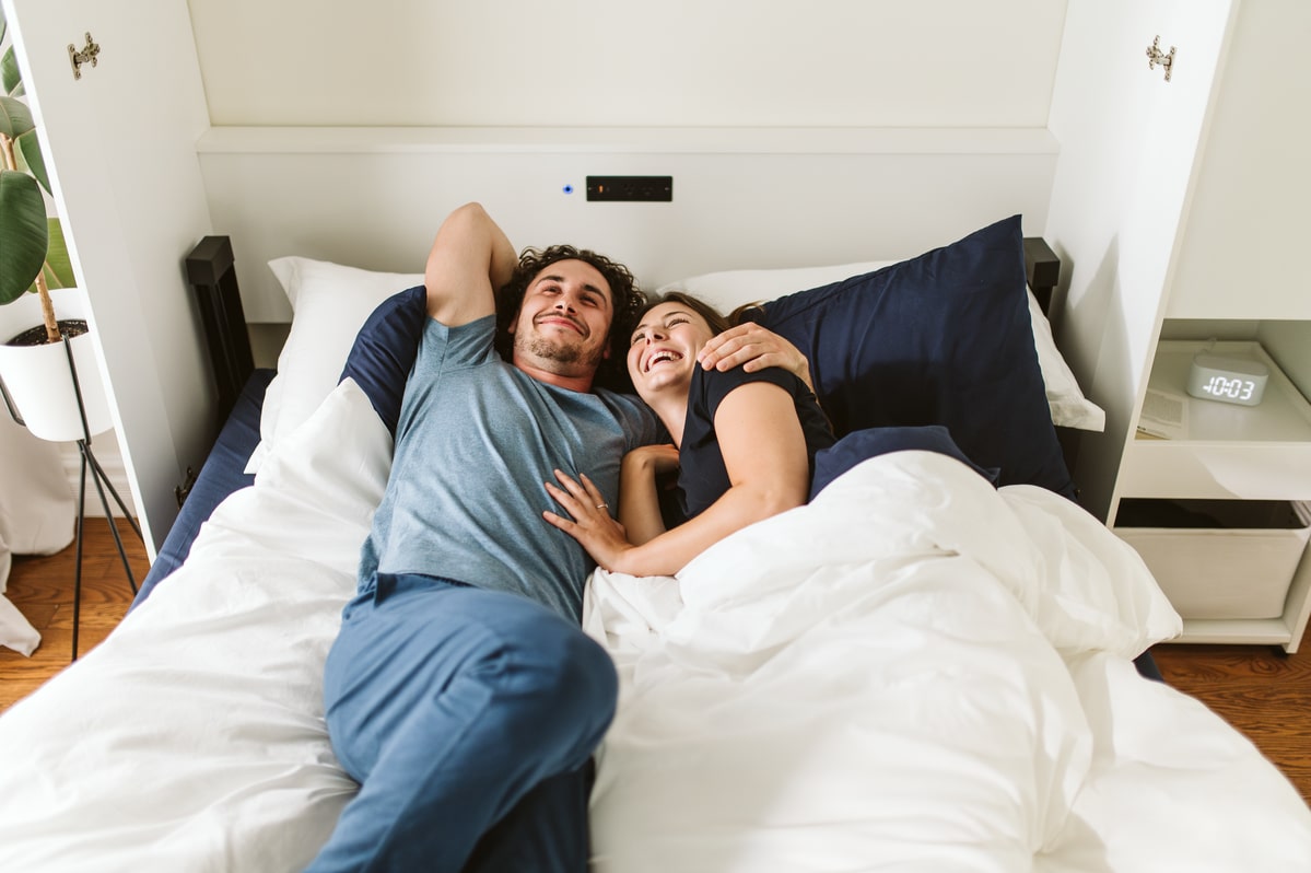 Couple lying in bed together in a bedroom.