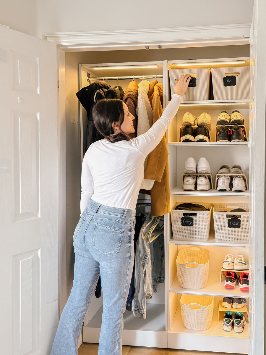 Person organizing shoes in the Florence collection closet with shelves and containers.