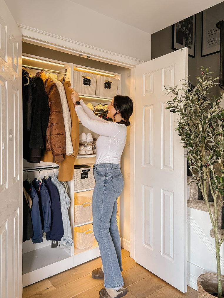 Person organizing clothes in a well-lit Florence collection walk-in closet.