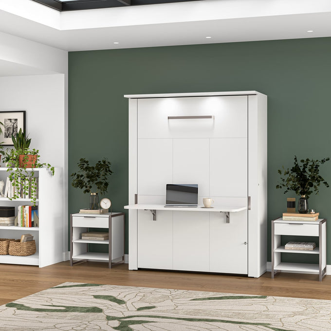 White wall-mounted Murphy bed with a desk in a room with green walls and wooden flooring.