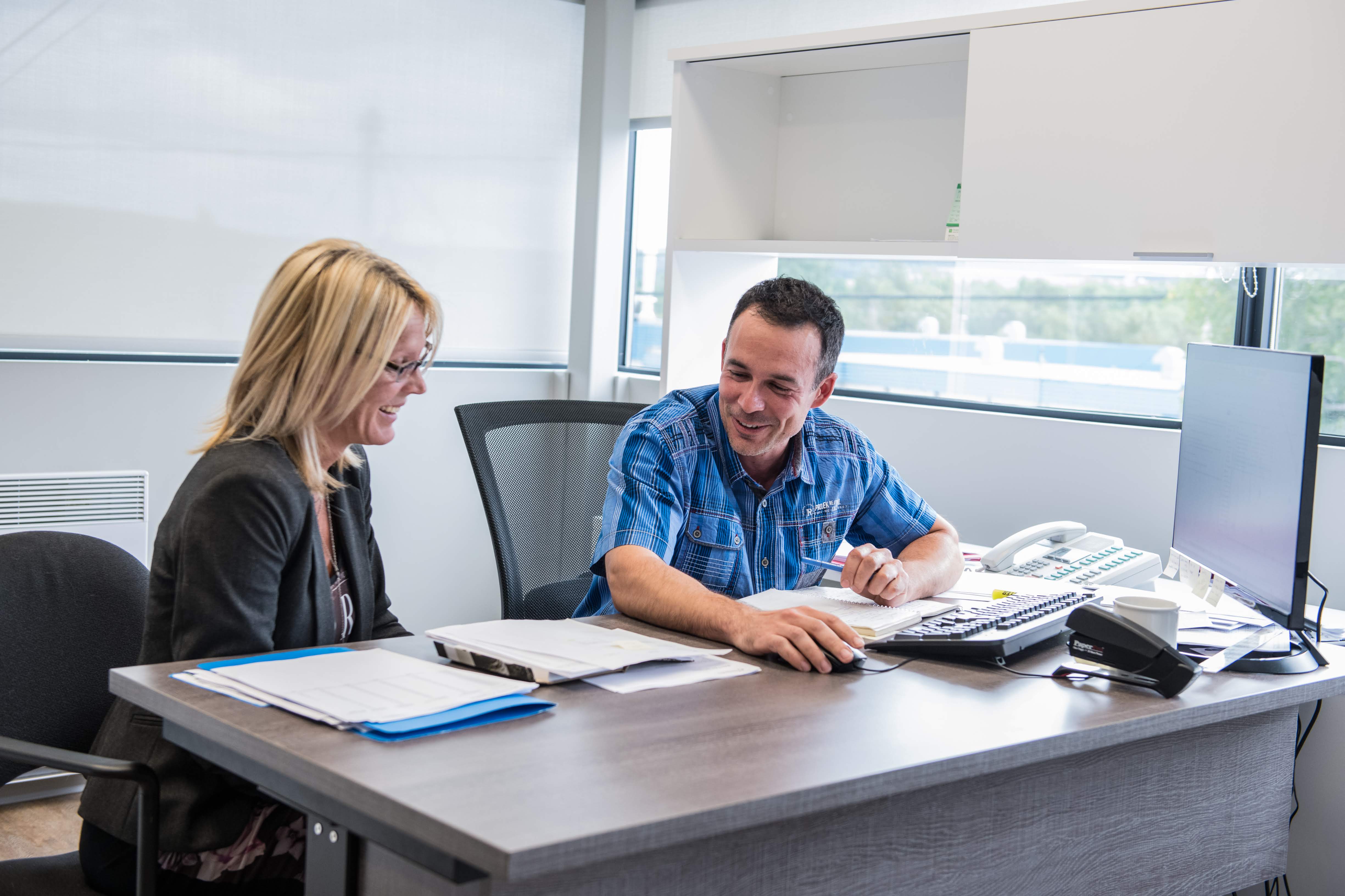 Two people working at a desk in an office setting.