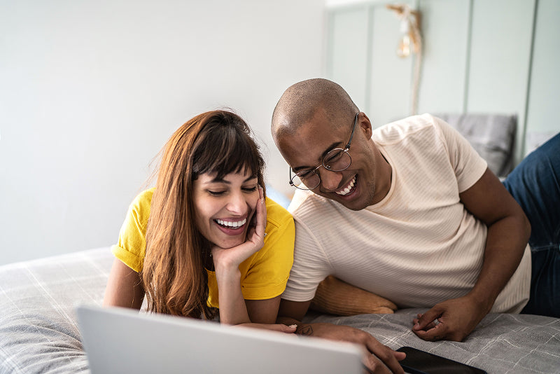 Couple lying in bed looking at the computer screen