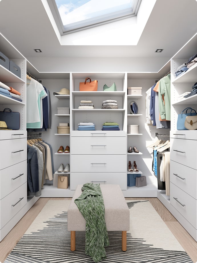 Modern walk-in closet with white shelves, drawers, and clothing items.