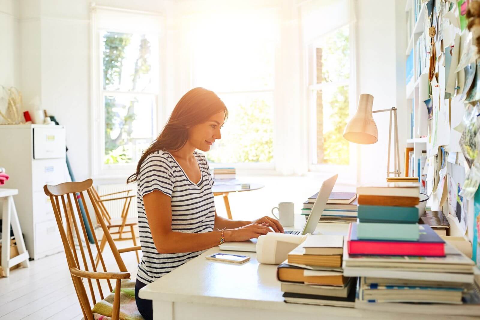 Woman working from home near window with sunlight