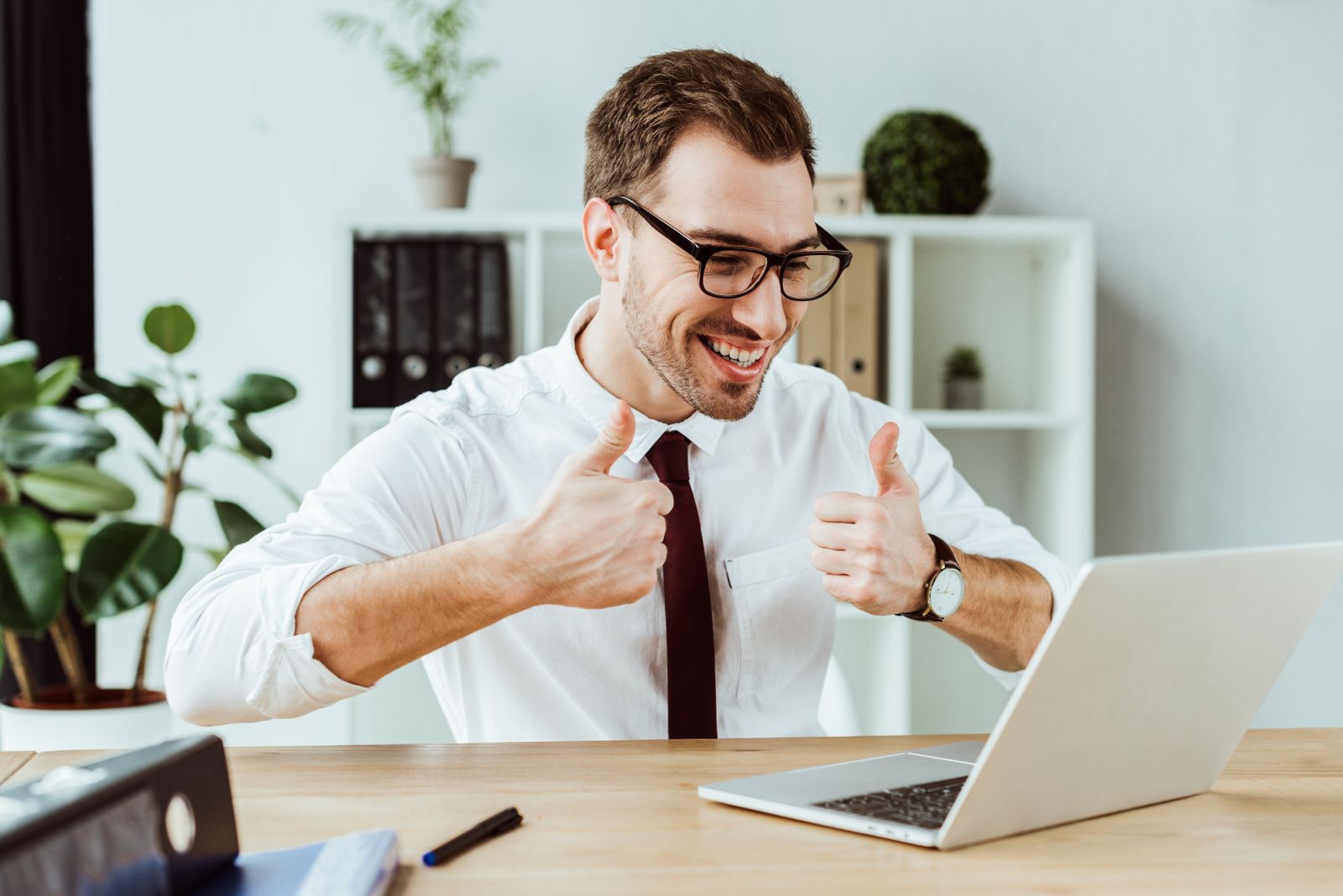 Businessman giving thumbs up through video chat