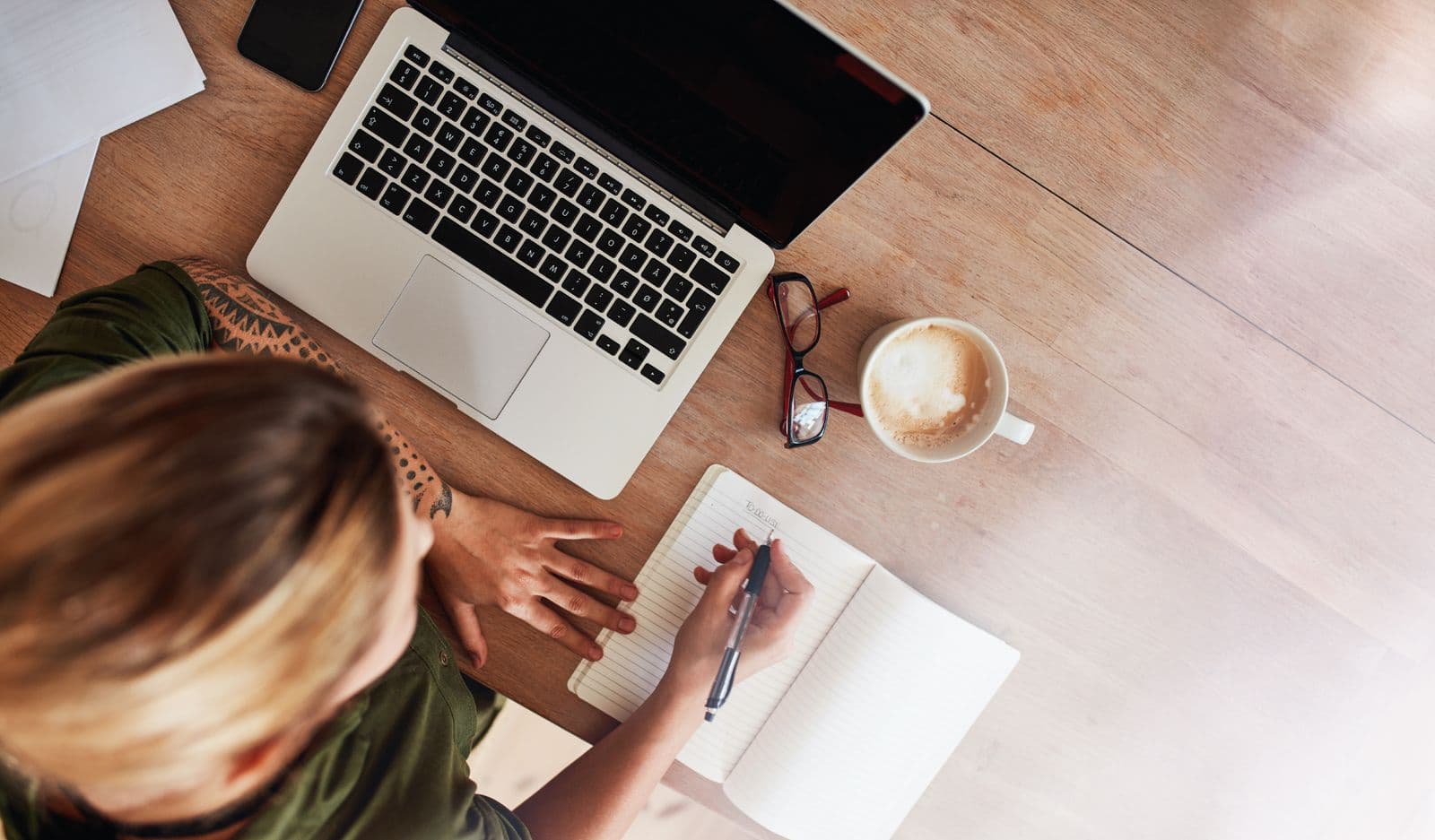 woman working on a large desktop with notebook and laptop