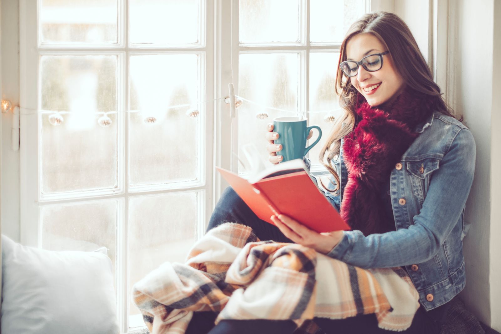 Woman reading a book by a window