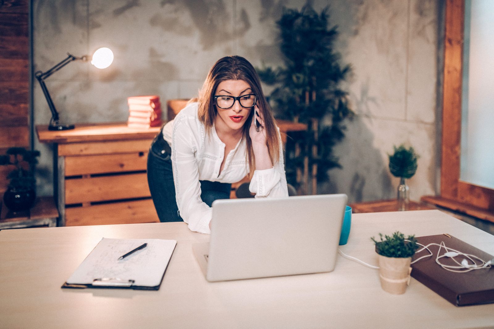 Woman using her laptop while speaking on the phone