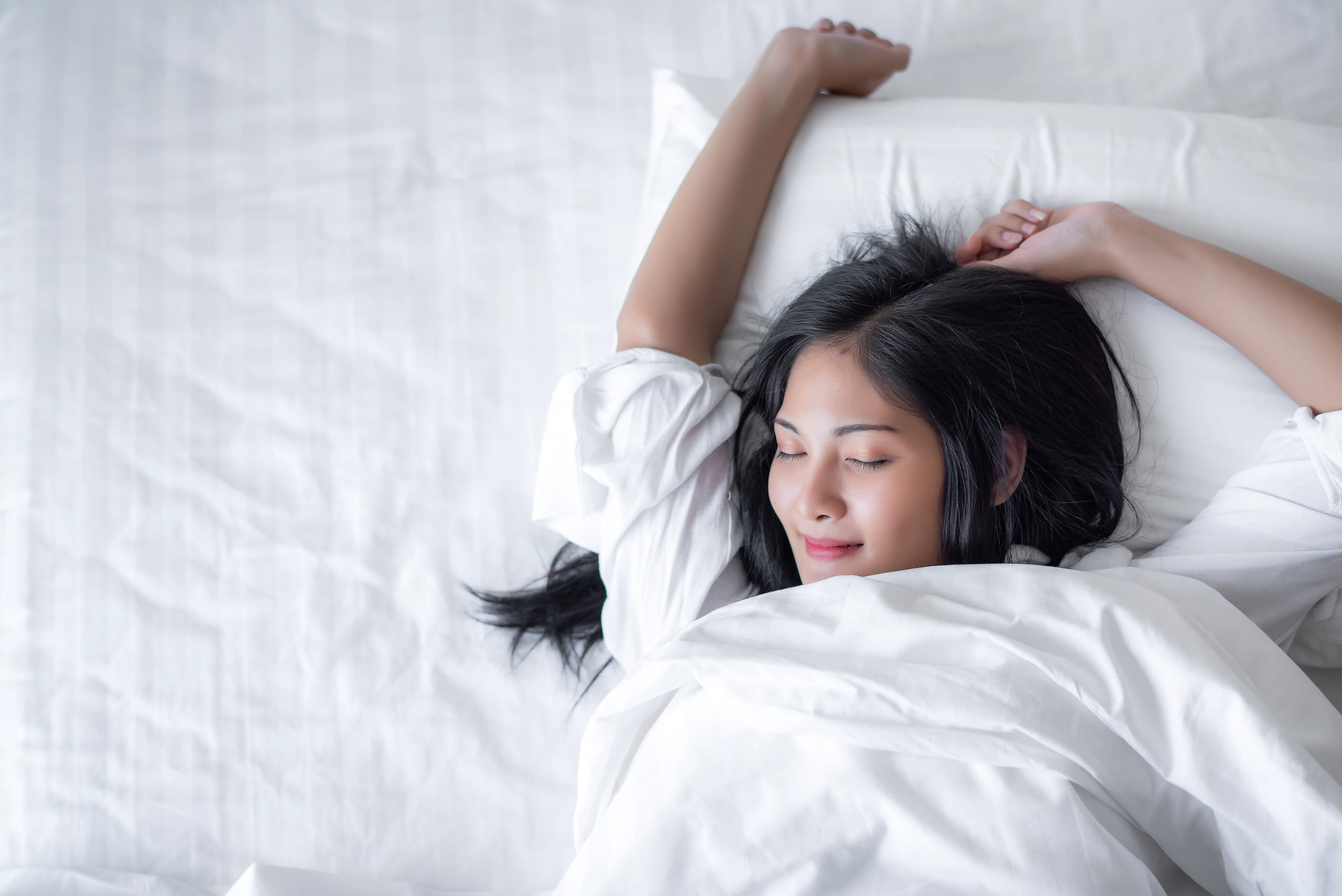 woman stretching in white bed