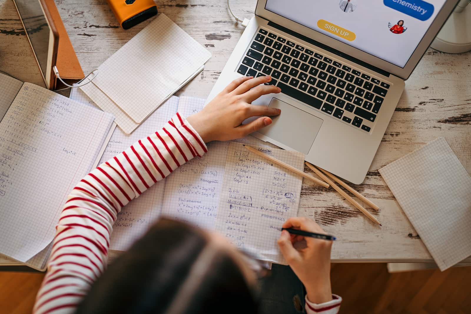 girl studying math with computer and pencils