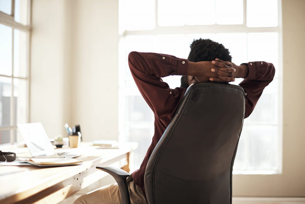 man leaning back in chair with hands behind his head