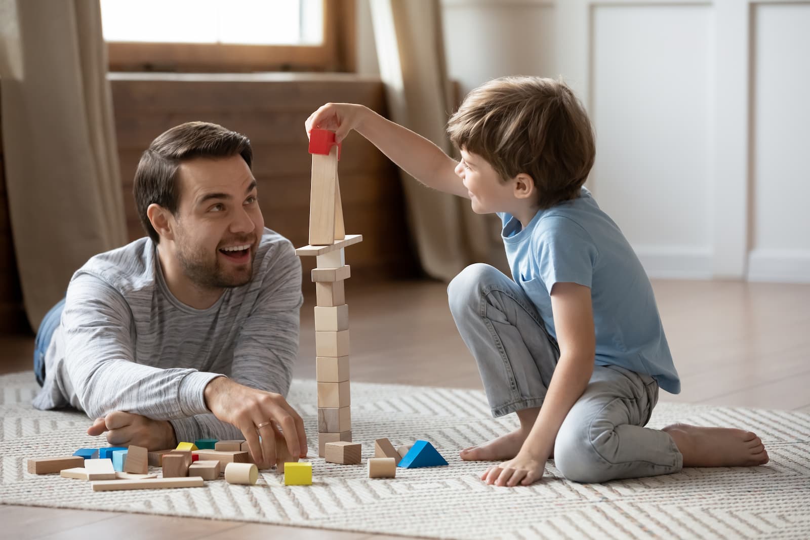 father and son playing together with wooden blocks building pyramids