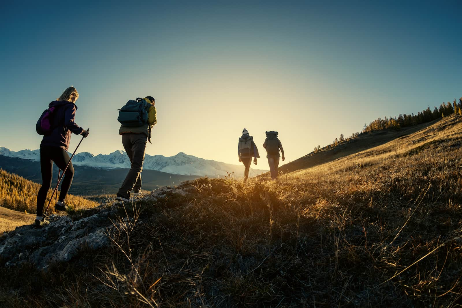 people hiking a mountain at sunset