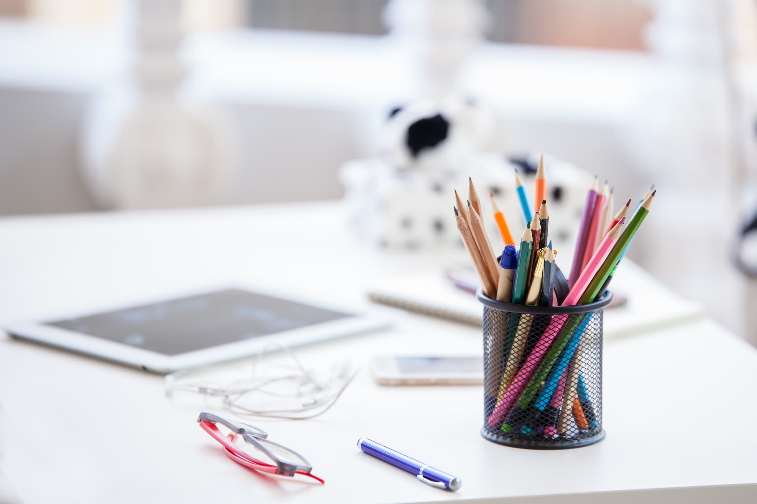 Pencil-holder, iPad and various supplies on a desktop