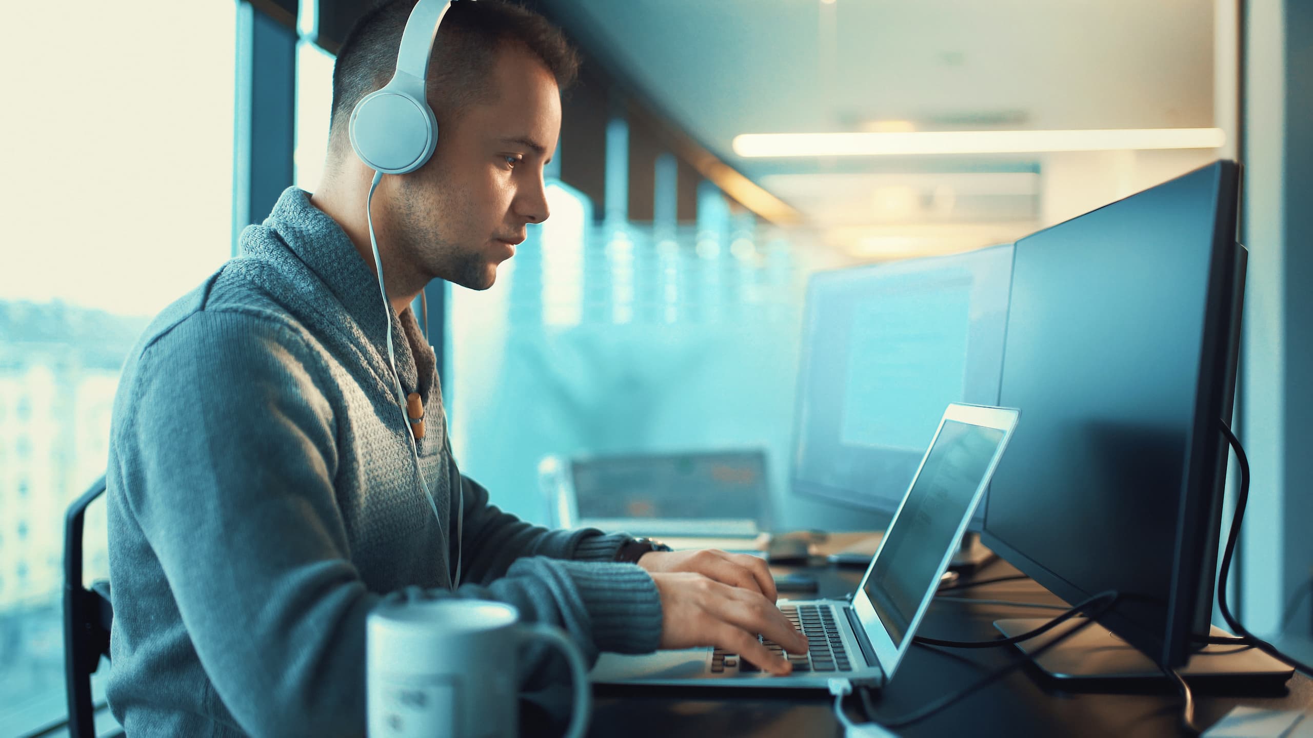 Man working on his laptop while wearing headphones