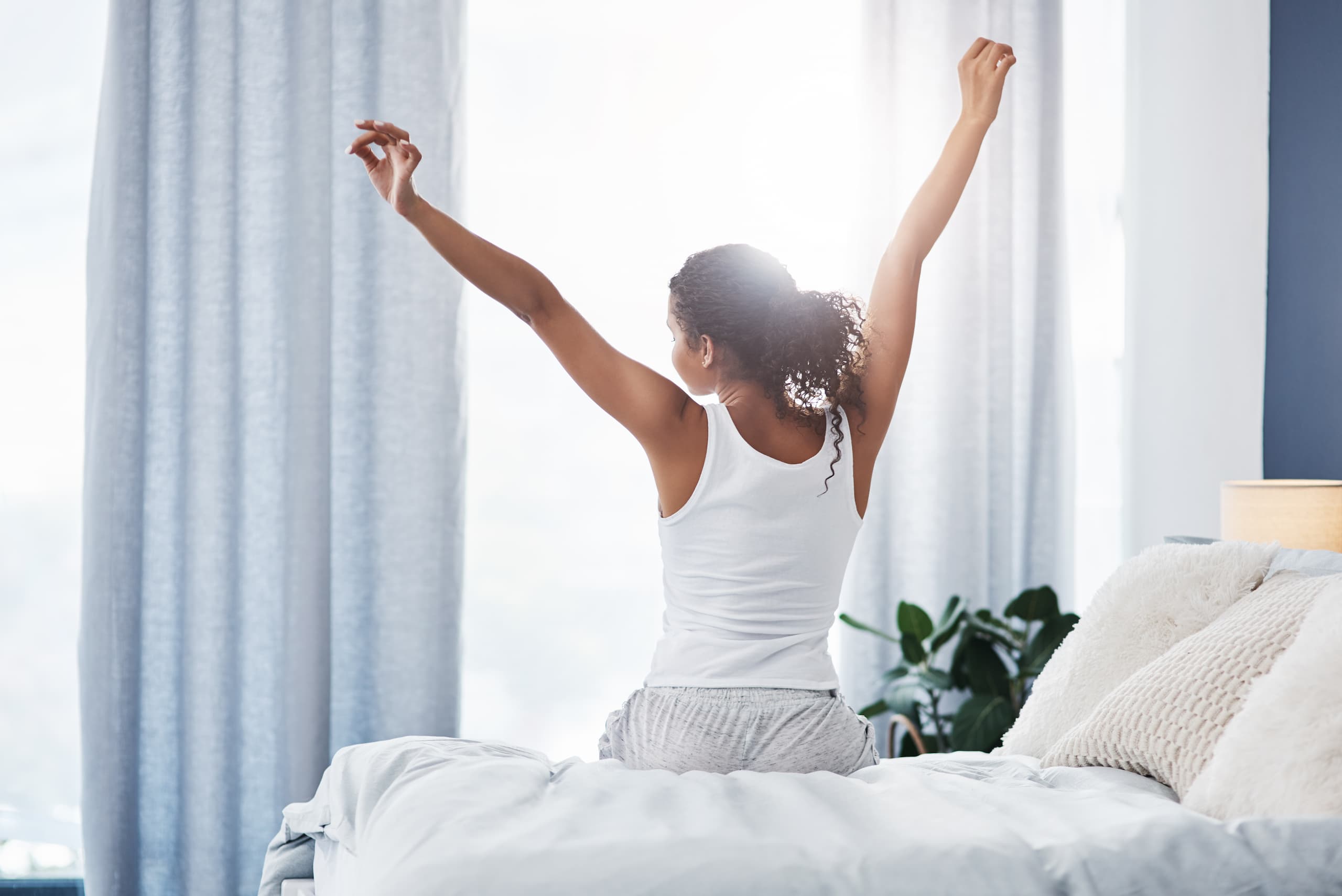 Woman stretching in bed on a bright morning