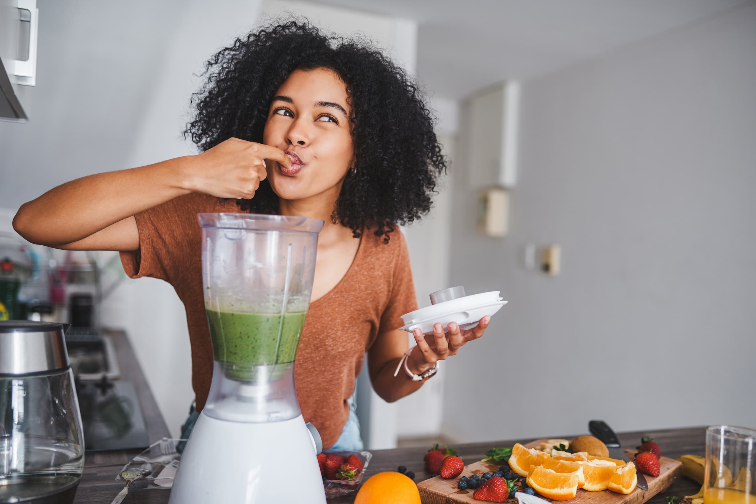Woman tasting her fruity smoothie as part of her work-from-home routine