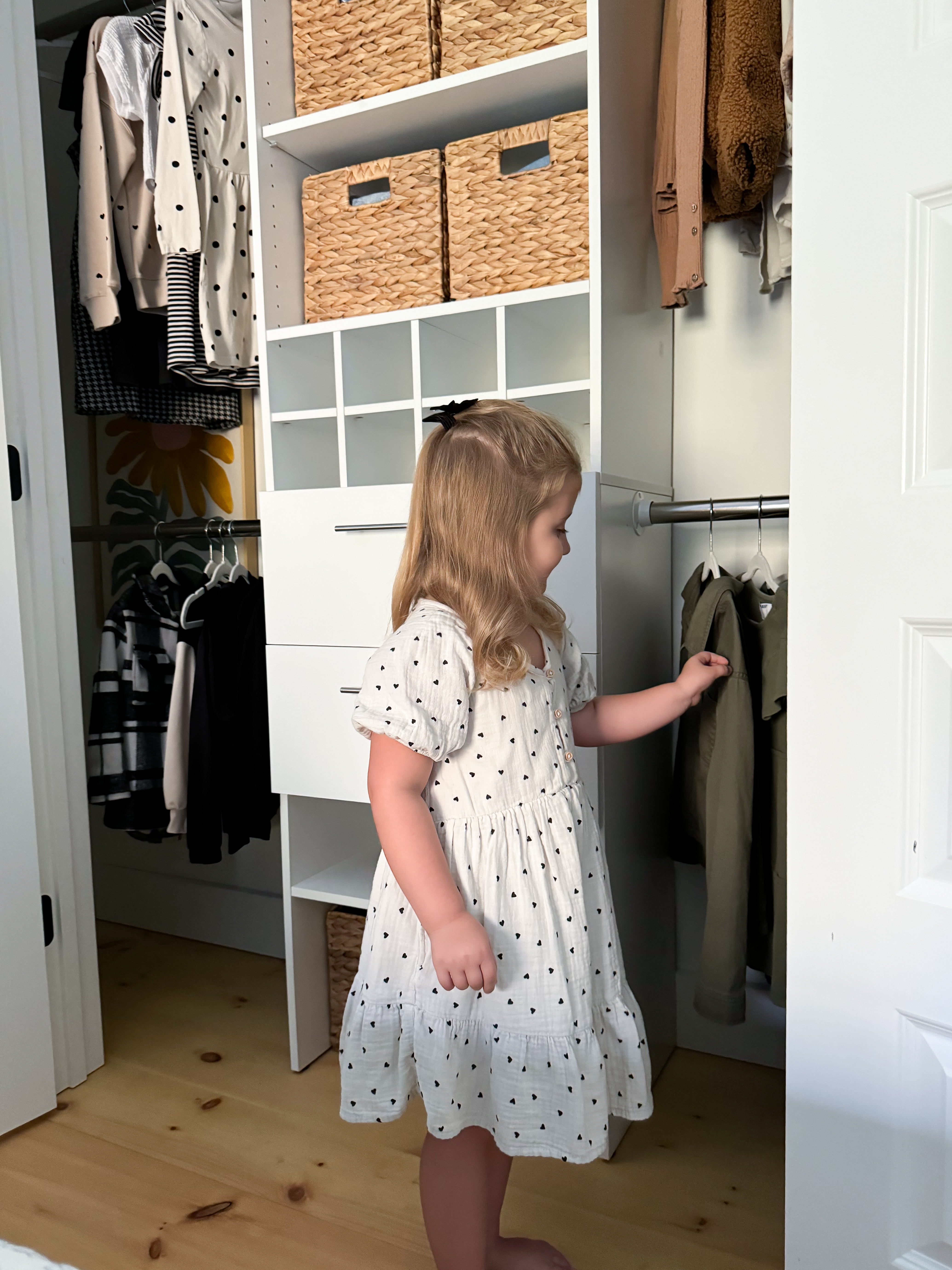 Child selecting clothes in a well-organized closet with drawers and baskets